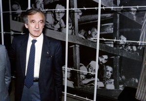 (FILES) This December 18, 1986, file photo shows Nobel Peace prize winner and writer Elie Wiesel (L) standing in front of a photo of himself (bottom 3rd from R) and other inmates, taken at the Buchenwald concentration camp in 1945, during his visit to the Holocaust Memorial Center "Yad Vashem" in Jerusalem. Wiesel, the Holocaust survivor, renowned writer and Nobel peace laureate who worked to keep alive the memory of Jews slaughtered during World War II, has died, Israel's Yad Vashem Holocaust centre said on July 2, 2016. / AFP PHOTO / SVEN NACKSTRAND